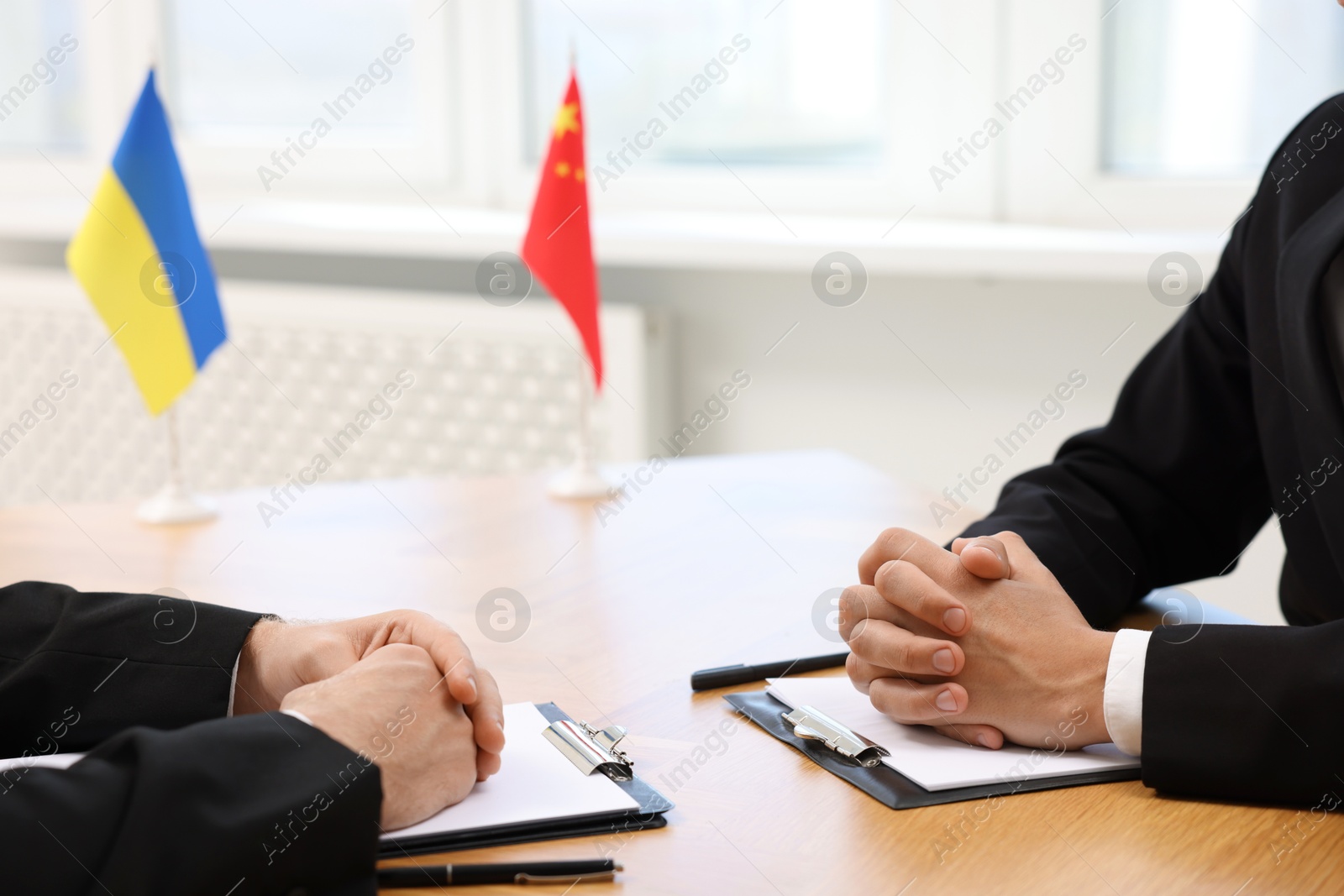 Photo of Diplomats negotiating during meeting at wooden table indoors, closeup