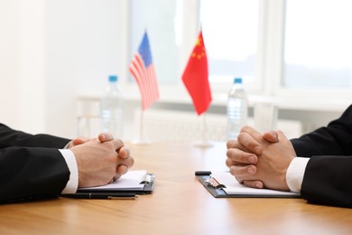 Photo of Diplomats negotiating during meeting at wooden table indoors, closeup