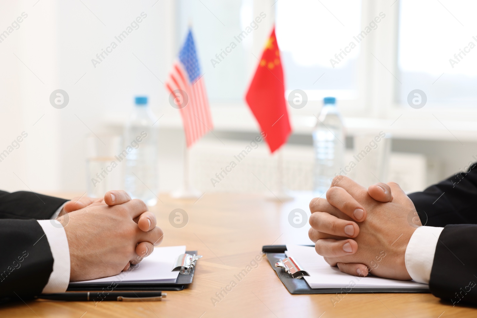 Photo of Diplomats negotiating during meeting at wooden table indoors, closeup