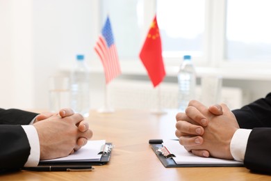 Diplomats negotiating during meeting at wooden table indoors, closeup