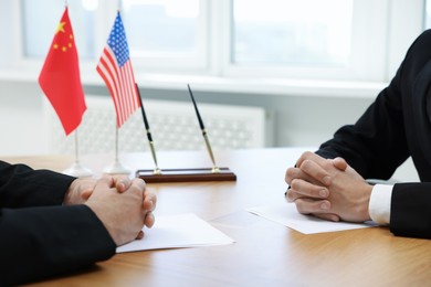 Diplomats negotiating during meeting at wooden table indoors, closeup