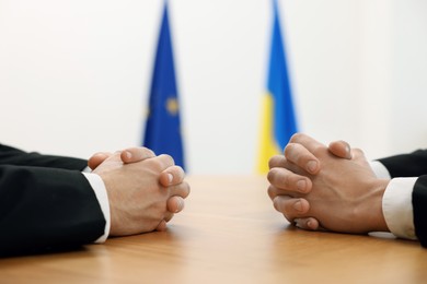 Diplomats negotiating during meeting at wooden table indoors, closeup