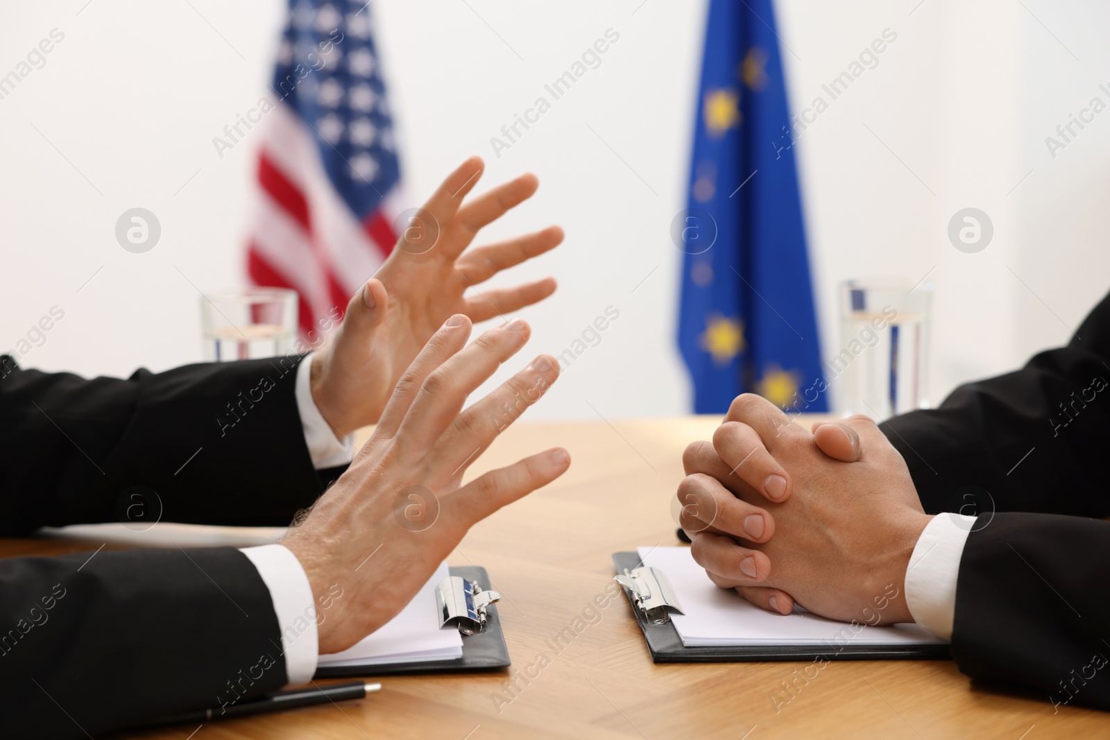 Photo of Diplomats negotiating during meeting at wooden table indoors, closeup