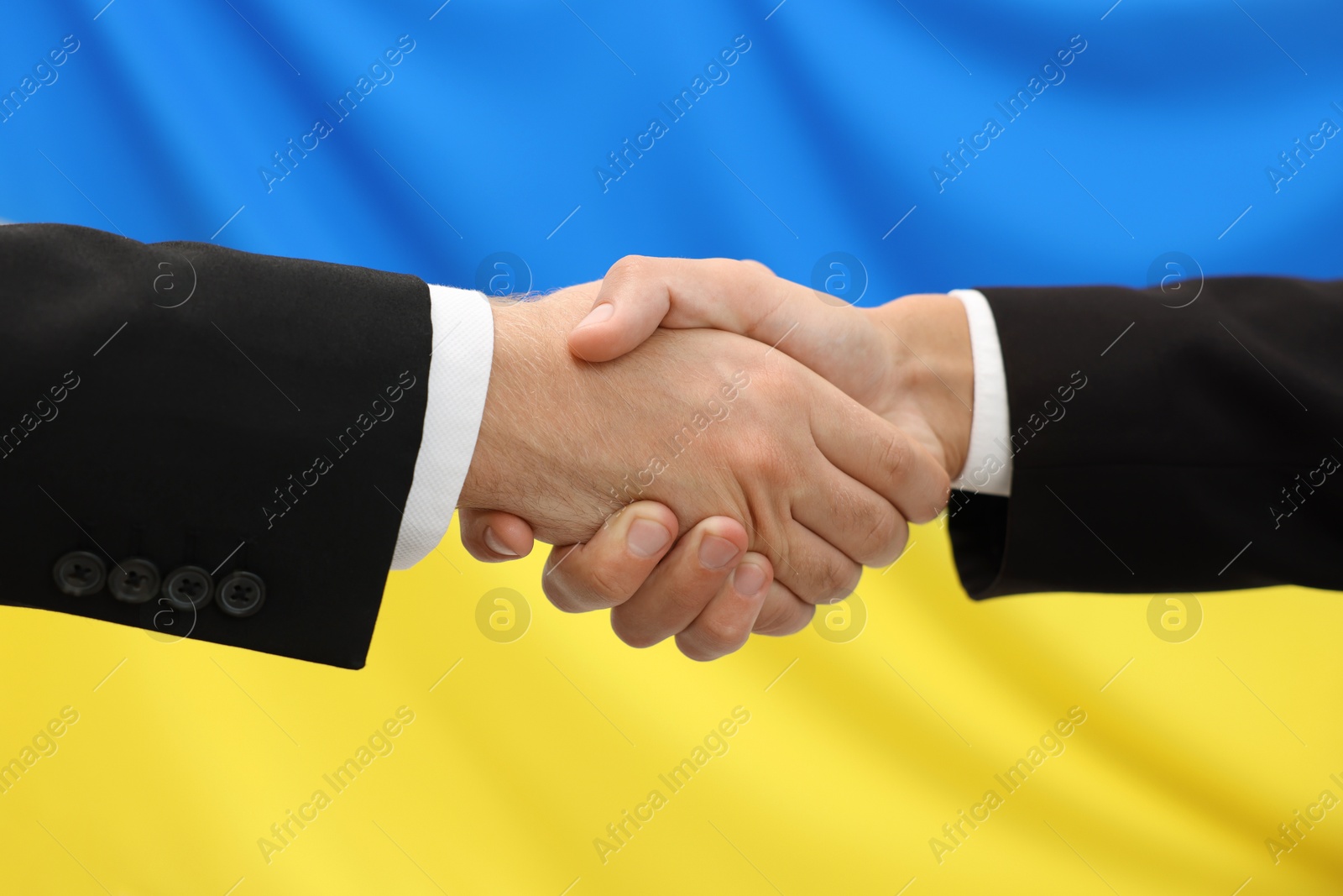 Photo of Diplomats shaking hands against flag of Ukraine, closeup