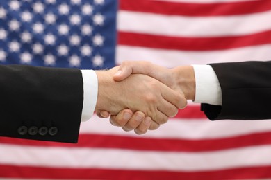 Photo of Diplomats shaking hands against flag of USA, closeup