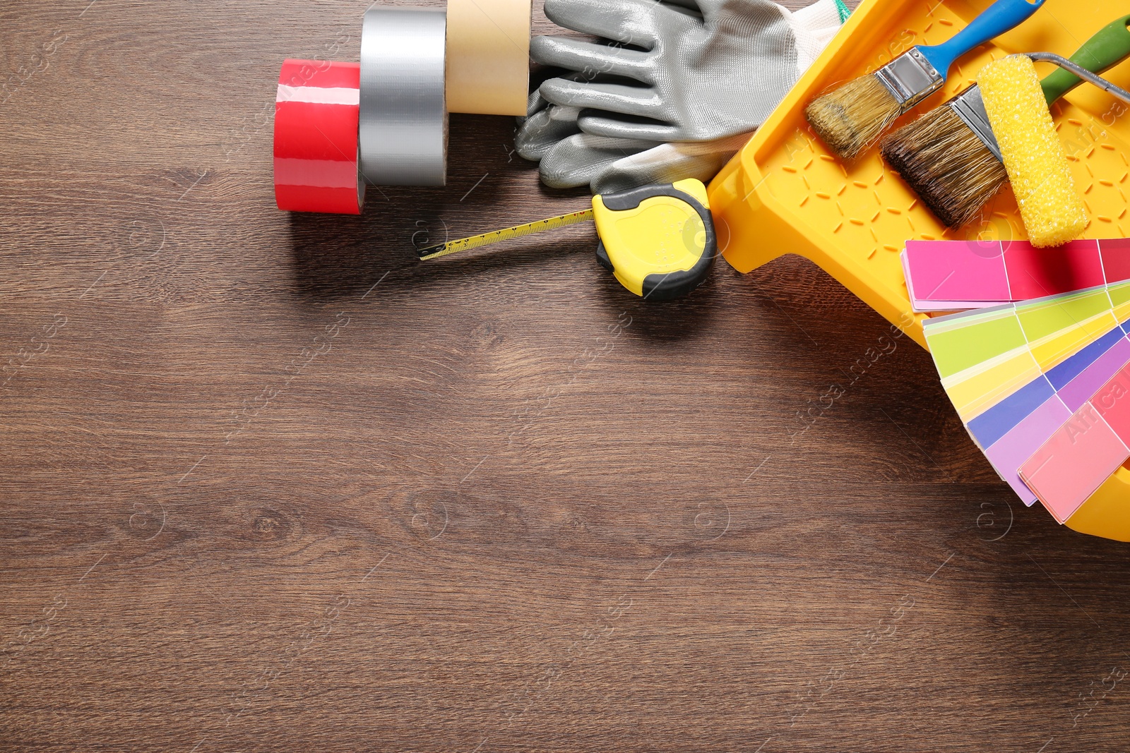 Photo of Flat lay composition with different painter's tools on wooden table, space for text. Decorating and design