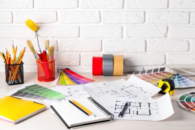 Photo of House plans and different decorator's tools on white table