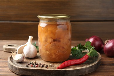 Photo of Canned meat in glass jar and fresh products on wooden table