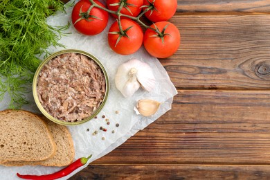 Photo of Canned meat in tin can served on wooden table, flat lay. Space for text