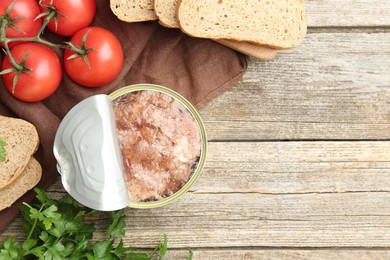 Photo of Canned meat in tin can served on wooden table, flat lay. Space for text