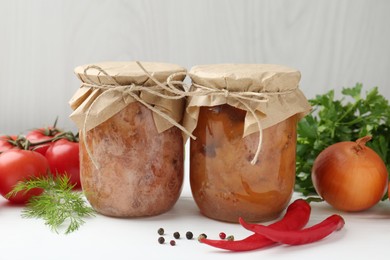 Photo of Canned meat in glass jars and fresh products on white wooden table