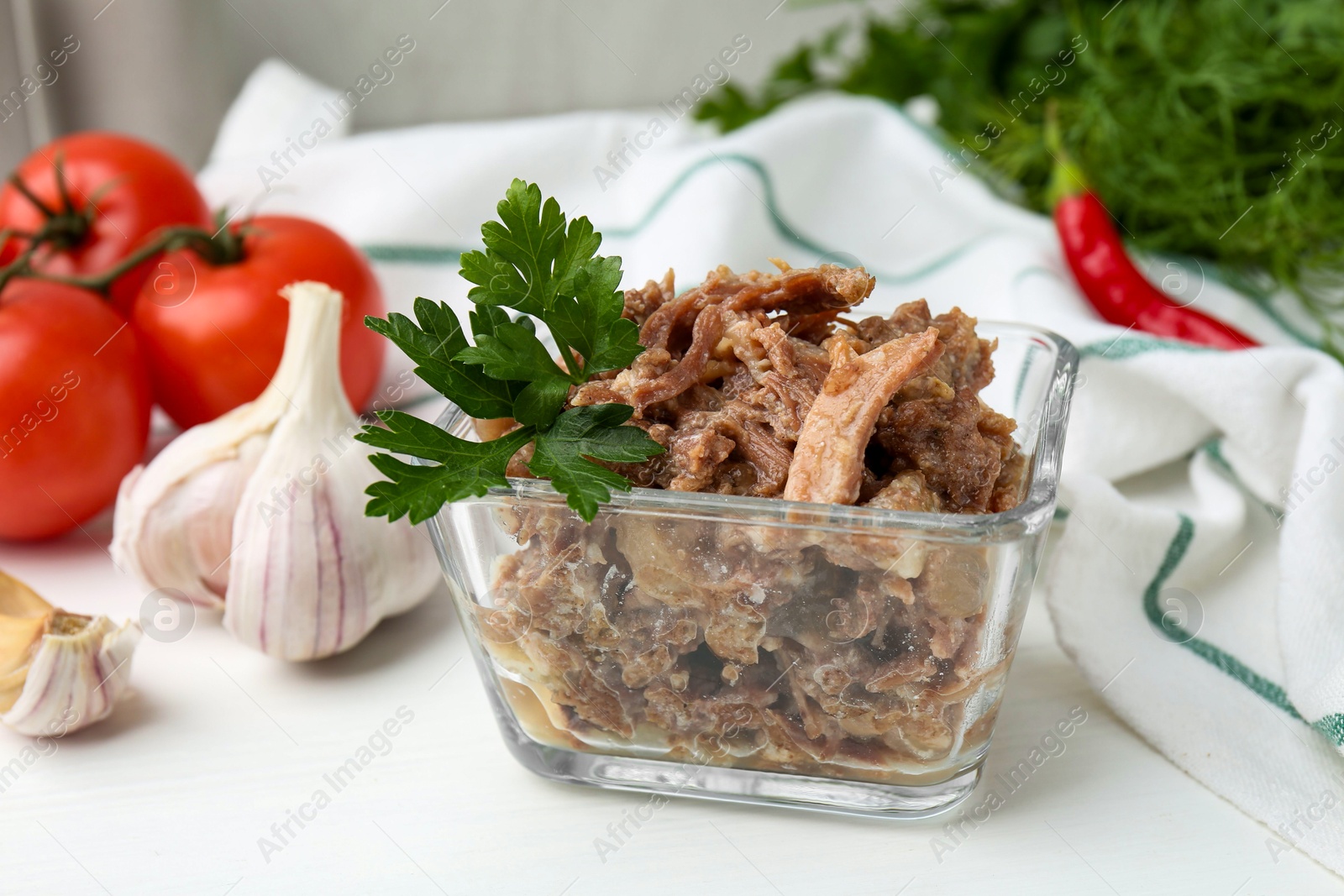 Photo of Canned meat with parsley in bowl on white table, closeup