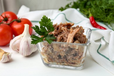 Photo of Canned meat with parsley in bowl on white table, closeup