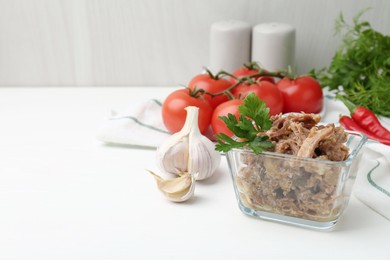 Photo of Canned meat with parsley in bowl and fresh vegetables on white wooden table, space for text