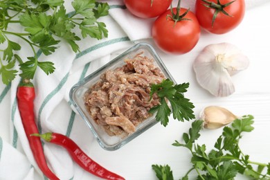 Photo of Canned meat in bowl and fresh vegetables on white wooden table, flat lay