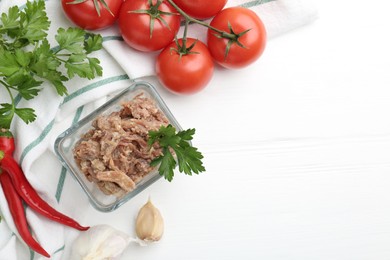 Photo of Canned meat in bowl and fresh vegetables on white wooden table, flat lay. Space for text