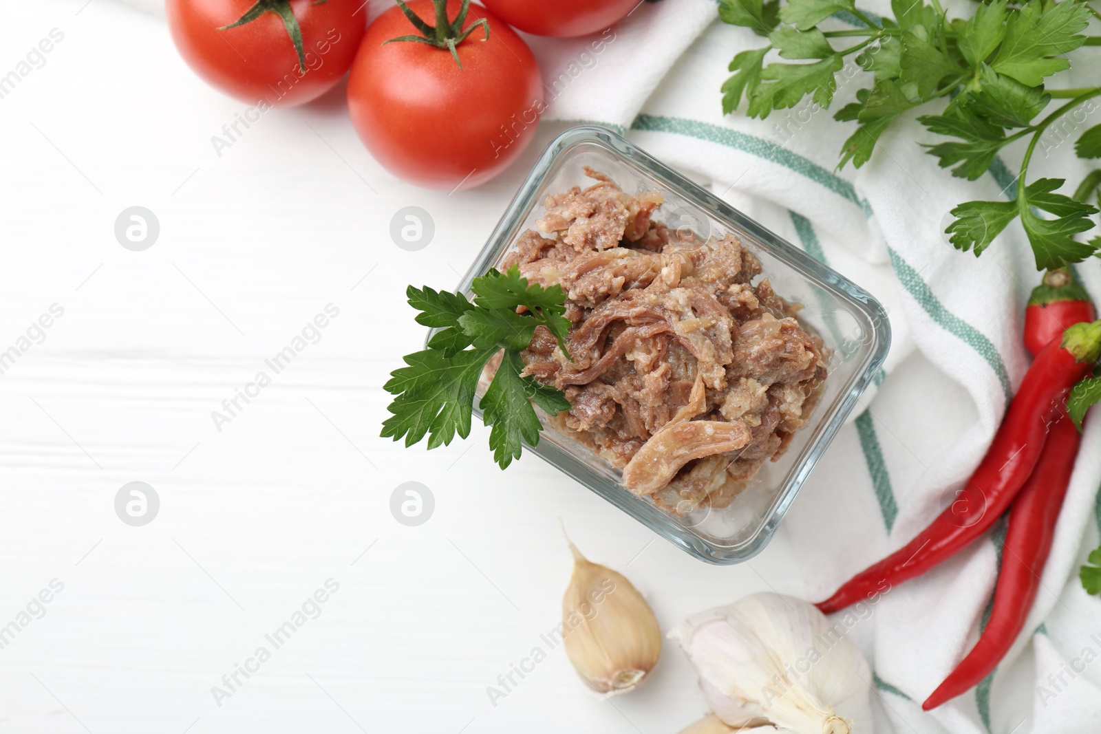 Photo of Canned meat in bowl and fresh vegetables on white wooden table, flat lay. Space for text