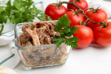 Photo of Canned meat with parsley in bowl on white table, closeup