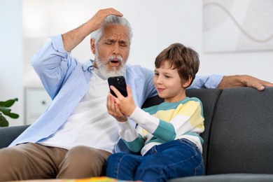 Grandpa and his grandson watching something on smartphone at home