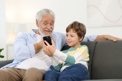 Photo of Grandpa and his grandson watching something on smartphone at home