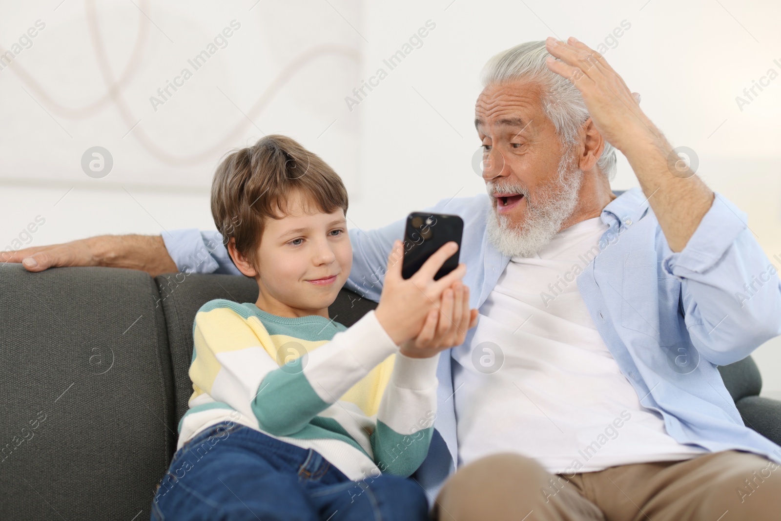 Photo of Grandpa and his grandson watching something on smartphone at home