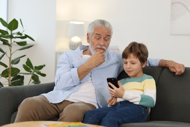 Photo of Grandpa and his grandson watching something on smartphone at home