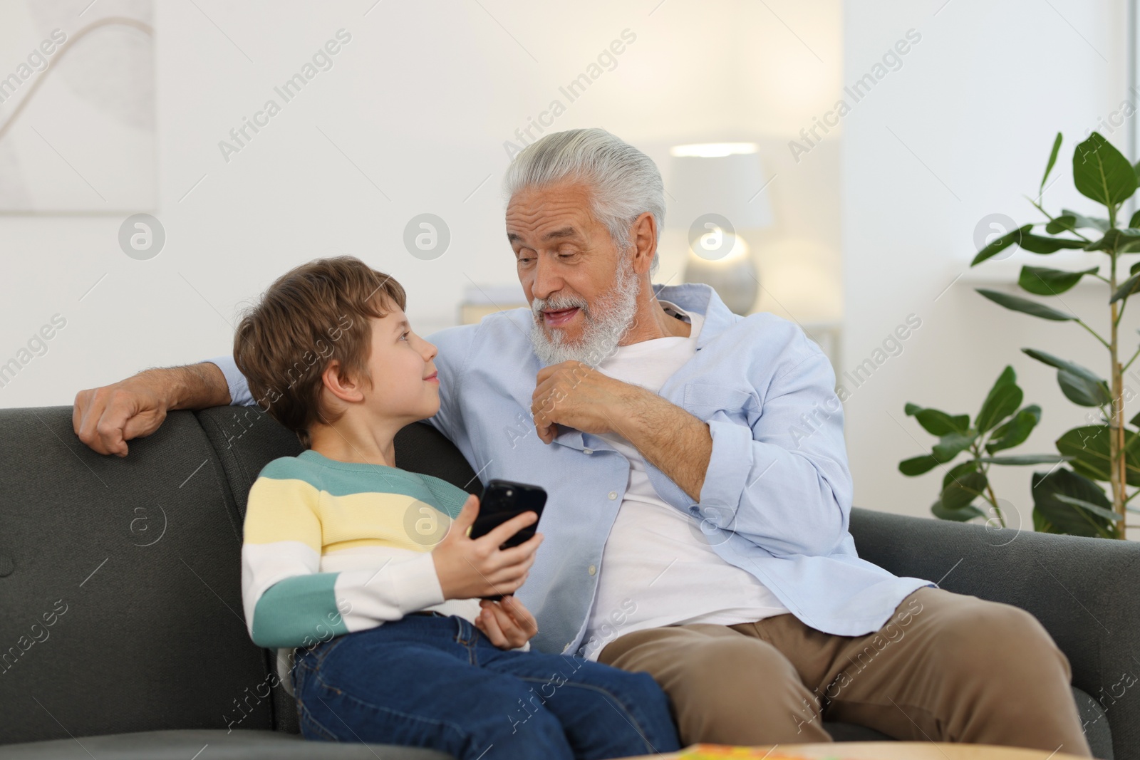 Photo of Grandpa and his grandson watching something on smartphone at home