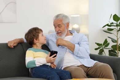 Grandpa and his grandson watching something on smartphone at home