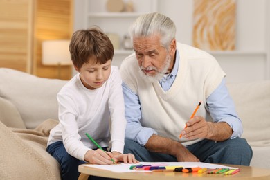 Photo of Grandpa and his grandson drawing at table indoors