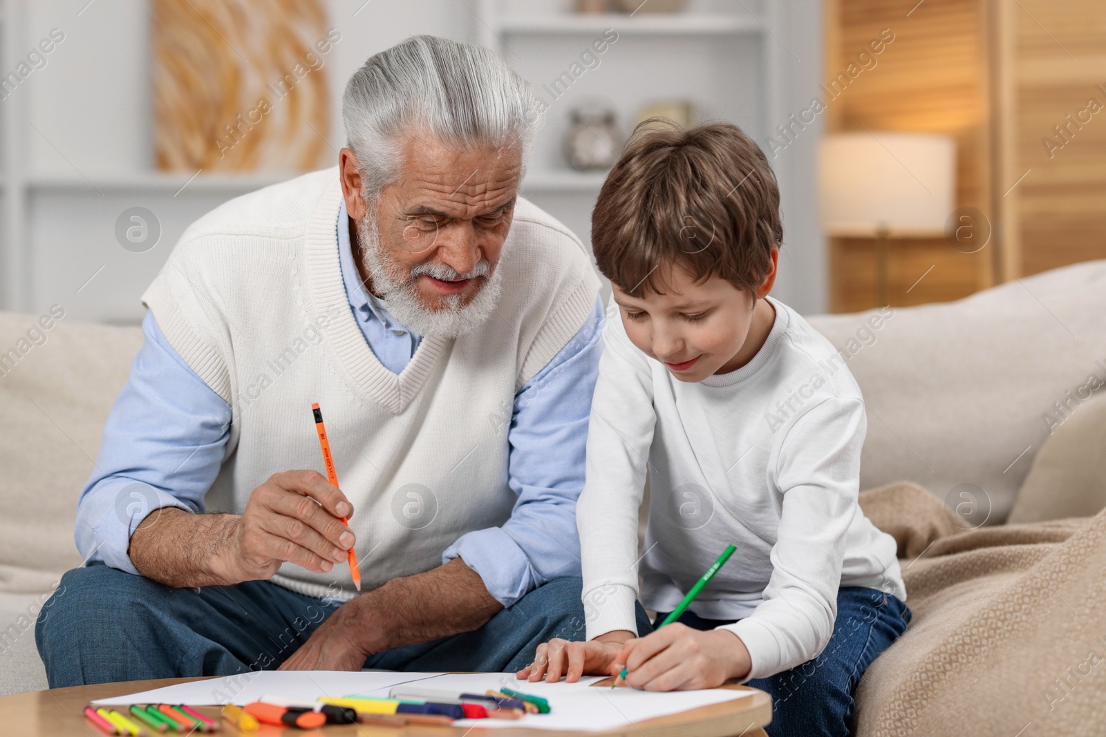 Photo of Grandpa and his grandson drawing at table indoors