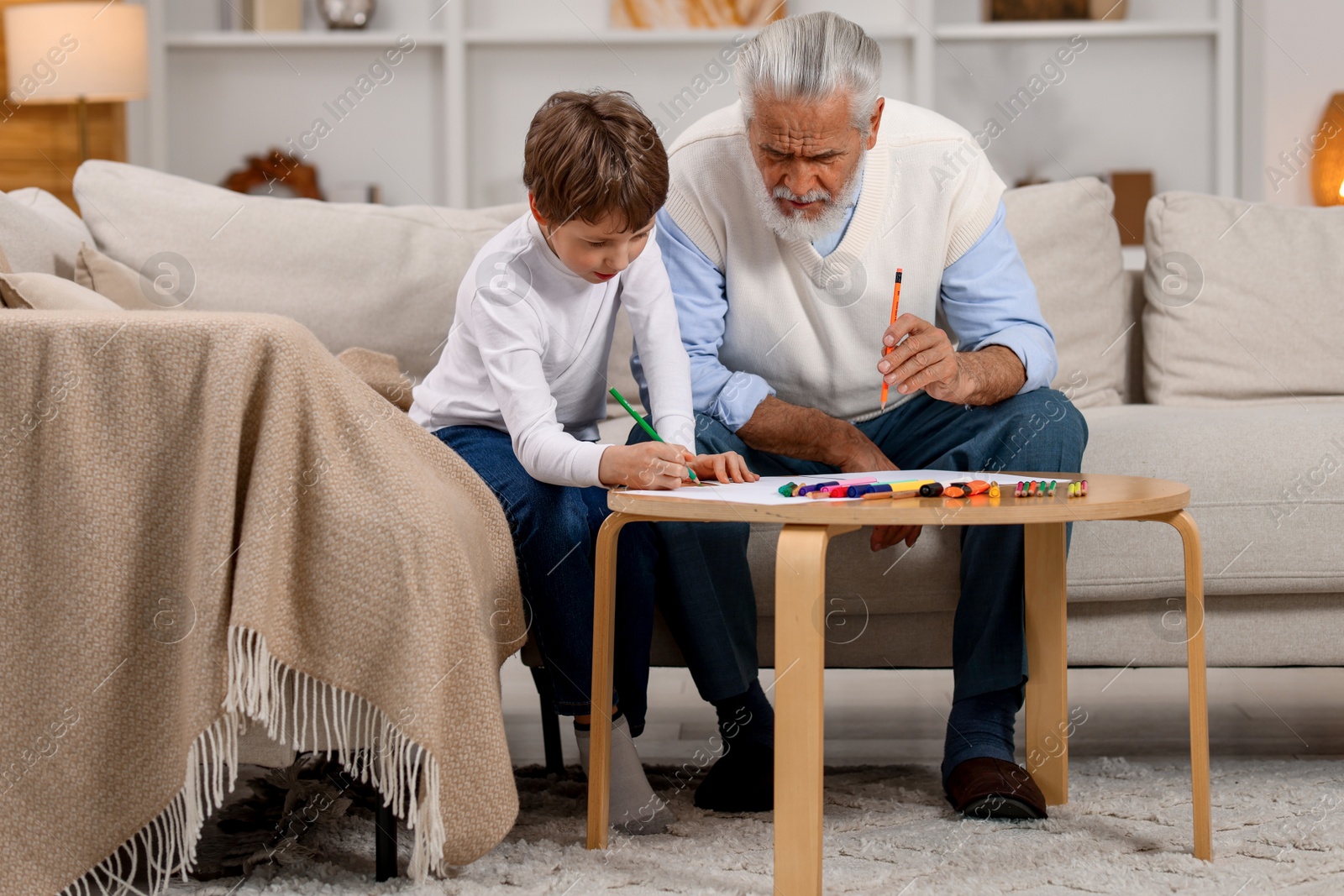 Photo of Grandpa and his grandson drawing at table indoors