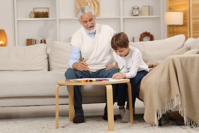 Photo of Grandpa and his grandson drawing at table indoors