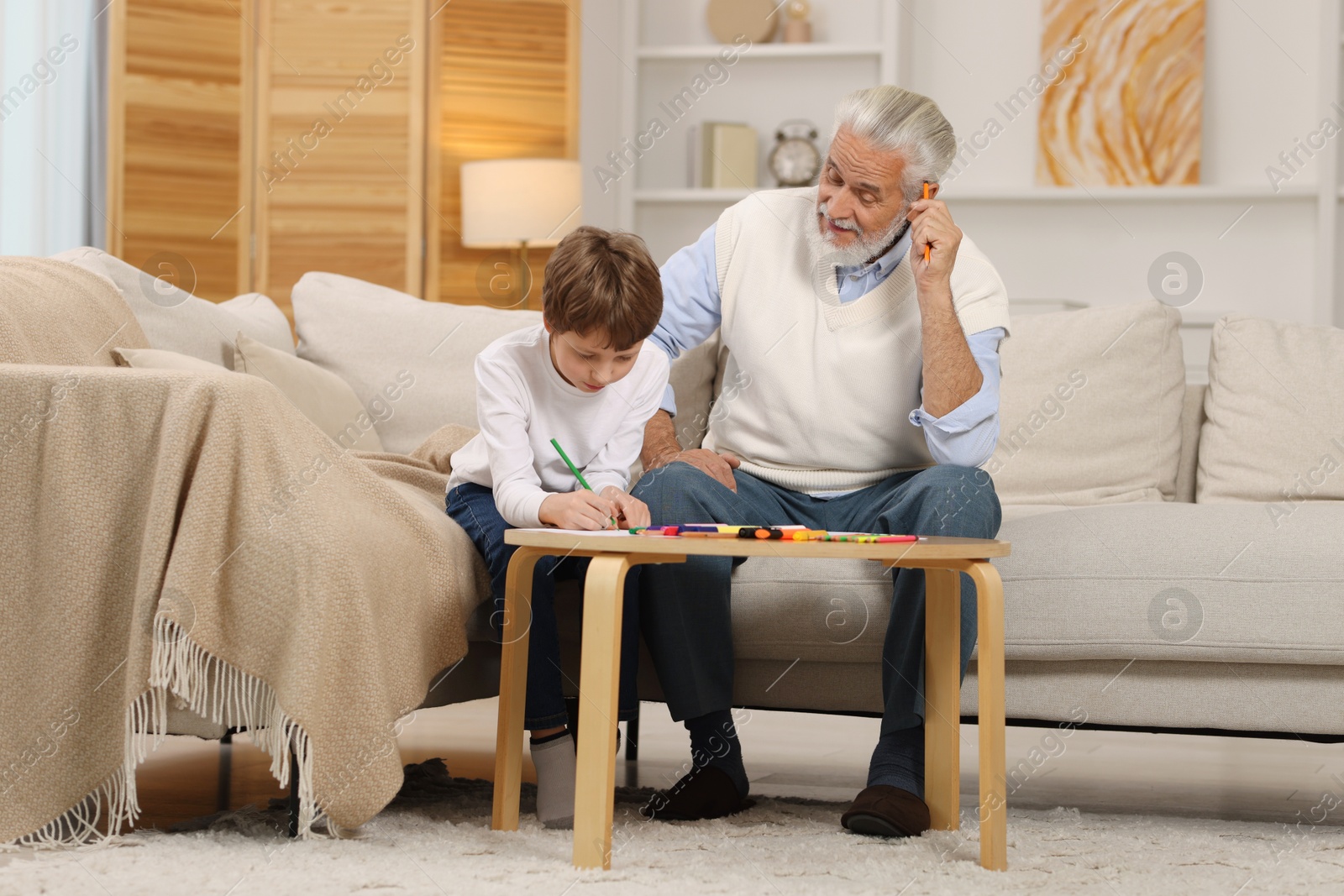 Photo of Grandpa and his grandson drawing at table indoors