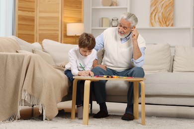 Photo of Grandpa and his grandson drawing at table indoors