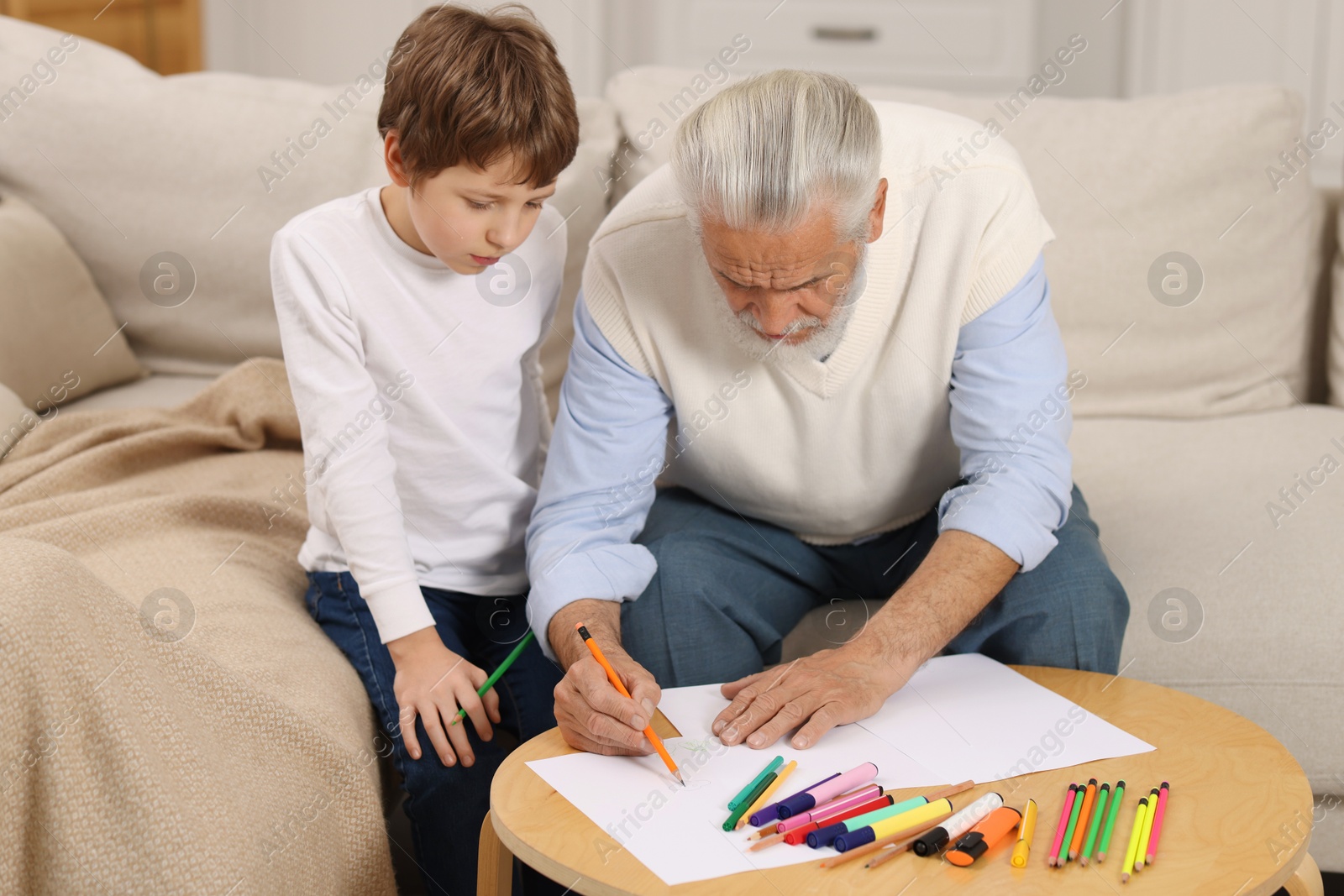 Photo of Grandpa and his grandson drawing at table indoors