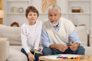 Photo of Grandpa and his grandson drawing at table indoors