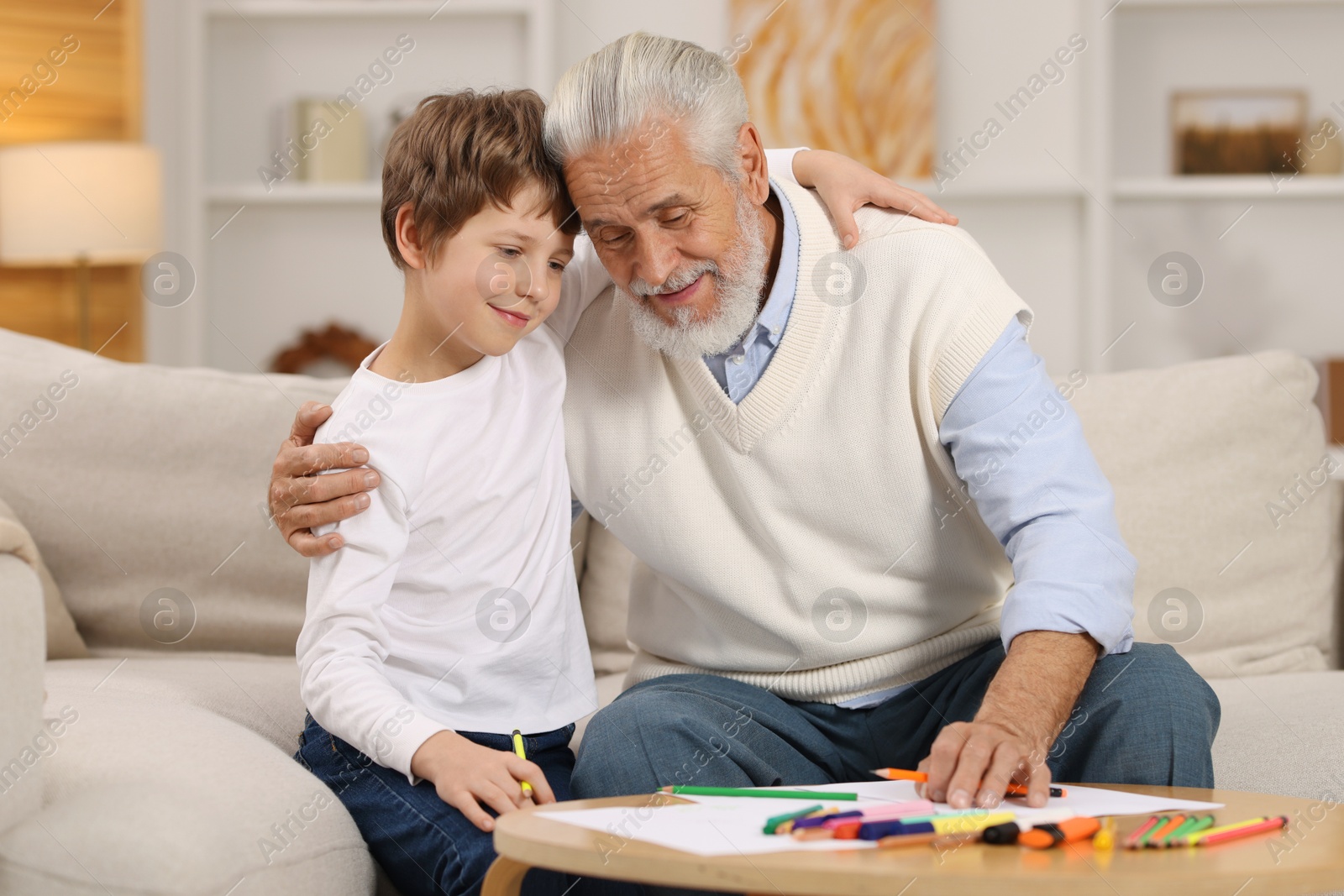 Photo of Grandpa and his grandson drawing at table indoors