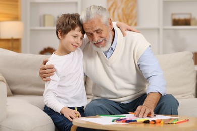 Photo of Grandpa and his grandson drawing at table indoors