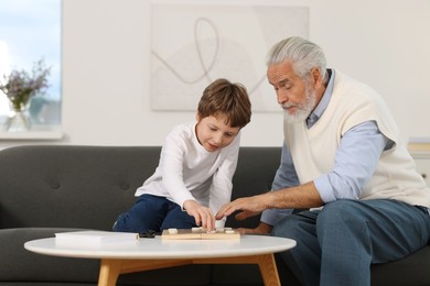 Photo of Grandpa and his grandson playing checkers at table indoors