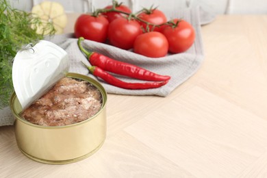 Photo of Canned meat in tin can and other products on wooden table. Space for text