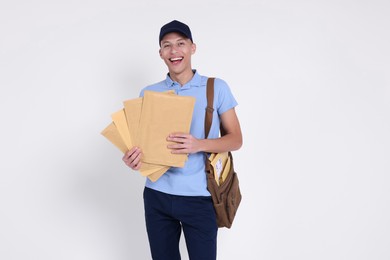 Photo of Happy postman with bag and envelopes on white background