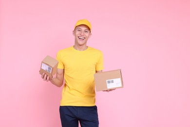 Photo of Happy postman with parcels on pink background. Space for text