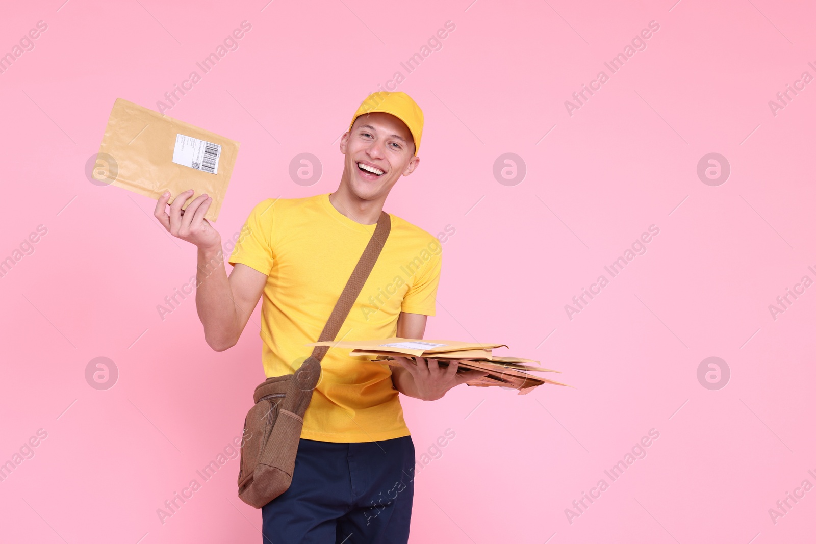 Photo of Happy postman with bag and envelopes on pink background. Space for text