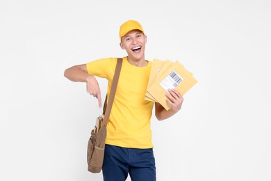 Happy postman with envelopes pointing at bag on white background