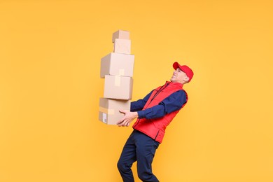 Photo of Emotional postman with parcels on yellow background. Space for text