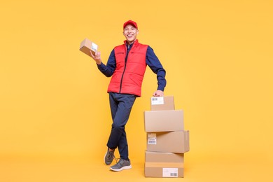 Photo of Happy postman with parcels on yellow background