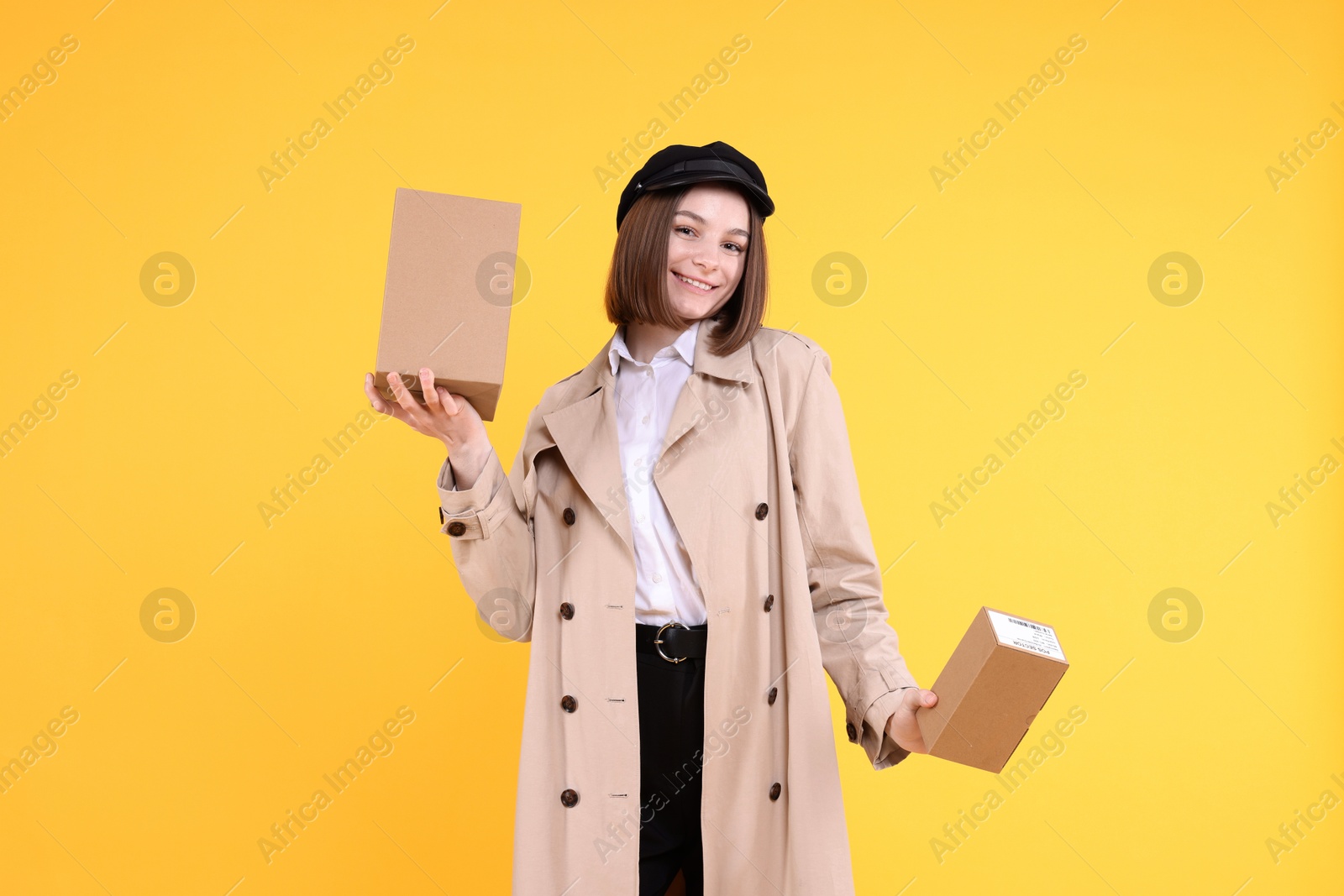 Photo of Happy postwoman with parcels on yellow background