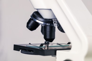 Photo of Science. Microscope with glass slide on light grey background, closeup