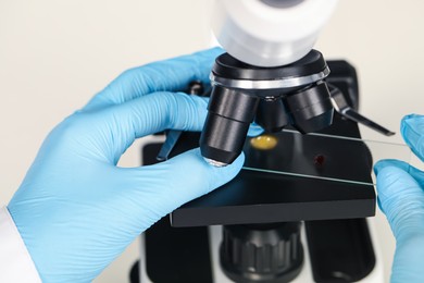 Scientist examining sample on slide under microscope, closeup