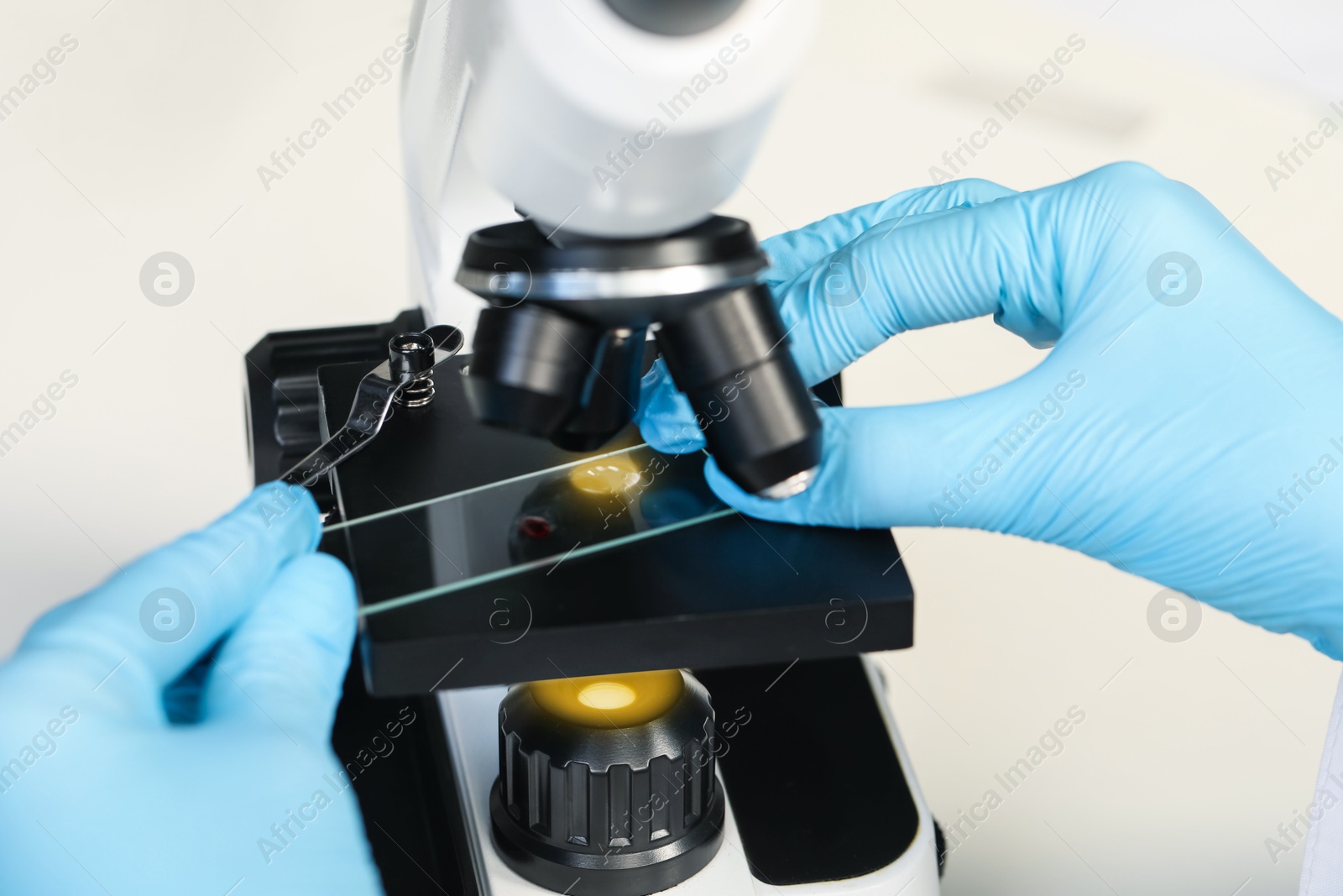 Photo of Scientist examining sample on slide under microscope, closeup